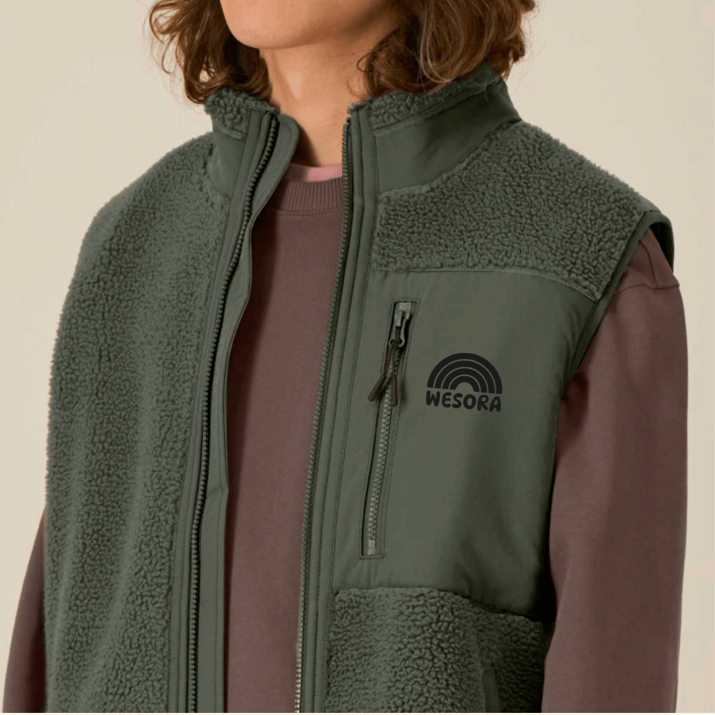 Sherpa Weste - Unisex mit Reißverschluss und Logo-Tasche, getragen über einem langärmeligen Shirt, Detailaufnahme des Oberkörpers.