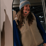 Sherpa Weste - Unisex mit Regenbogen-Logo, getragen von junger Frau vor Spiegel, in Innenraum, kombiniert mit Mütze und Halswärmer.