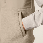 Sherpa Weste - Unisex mit seitlicher Tasche, getragen von einer Person in grauem Langarmshirt, fotografiert in Nahaufnahme mit Hand in der Tasche.