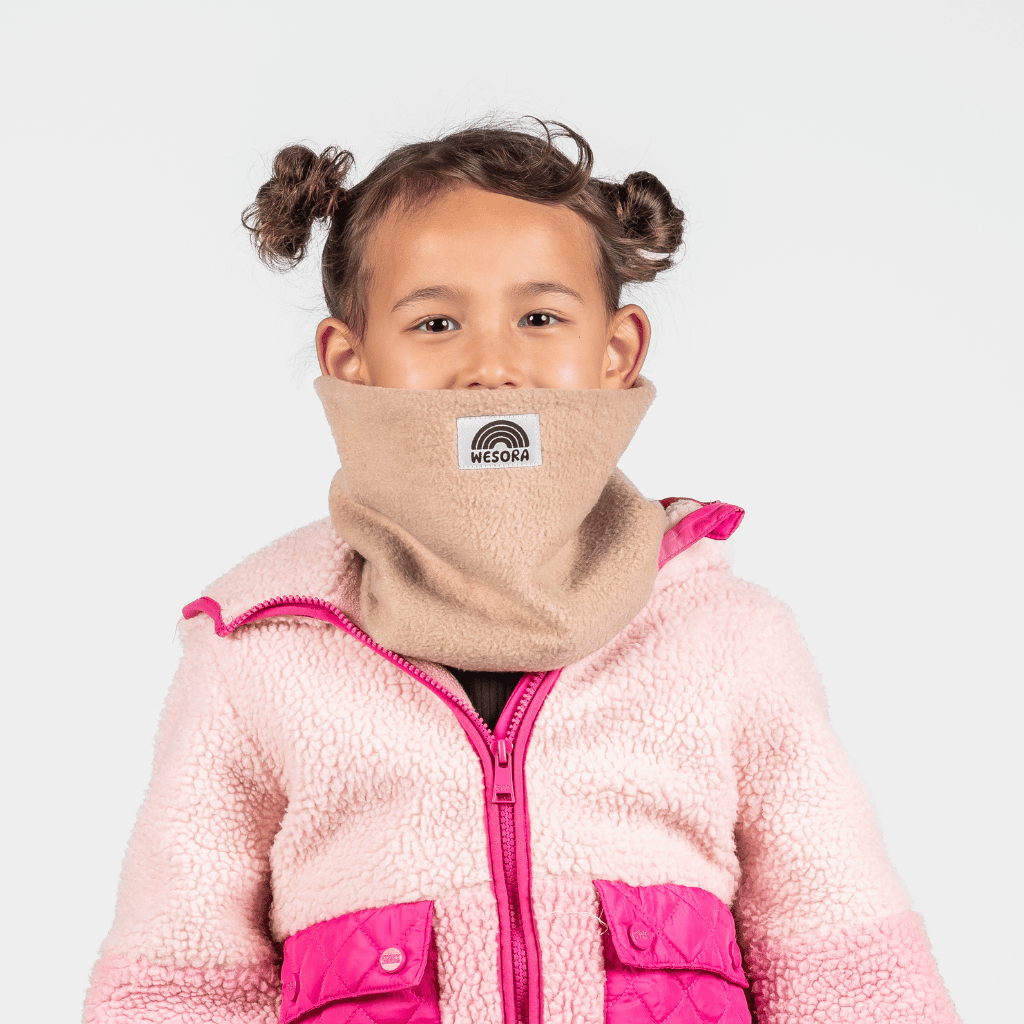 Fleece Neckwarmer - The Teddy Kid, getragen von einem Kind mit zwei kleinen Duttbuns, kombiniert mit einer rosa Sherpa-Jacke, fotografiert vor neutralem Hintergrund.