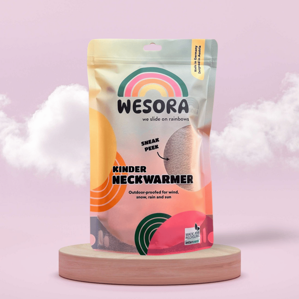 Fleece Neckwarmer - The Teddy Kid in farbenfrohem Beutel, auf Podest platziert. Outdoor-tauglich, recycelbar, hergestellt in Deutschland, designt in Österreich.