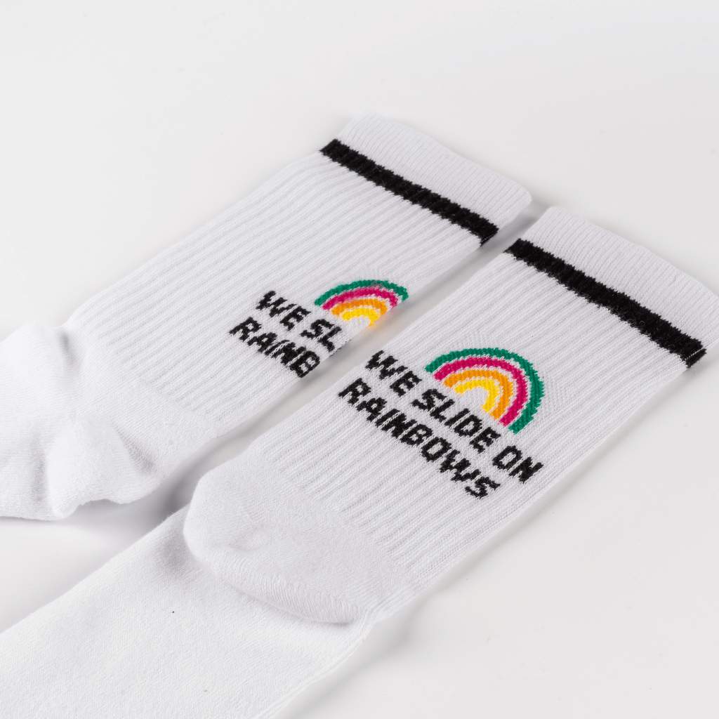 Socken - WESORA mit Regenbogenmotiv und WE SLIDE ON RAINBOWS-Schriftzug, flach ausgebreitet, sportlicher Stil, schwarze Streifen unter dem Bund.