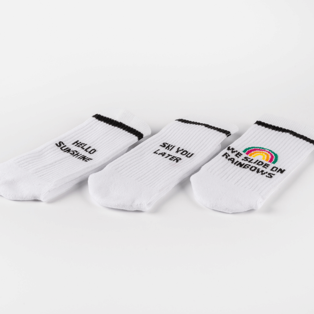 Socken-Bundle mit drei Designs: „HELLO SUNSHINE“, „SEE YOU LATER“ und „WE SLIDE ON RAINBOWS“. Ideal zum Mixen und Matchen, auf weißem Hintergrund.