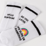 Socken-Bundle mit drei Designs: HELLO SUNSHINE, SEE YOU LATER, WE SLIDE ON RAINBOWS mit Regenbogen-Emblem, ideale Kombination für jeden Stil.