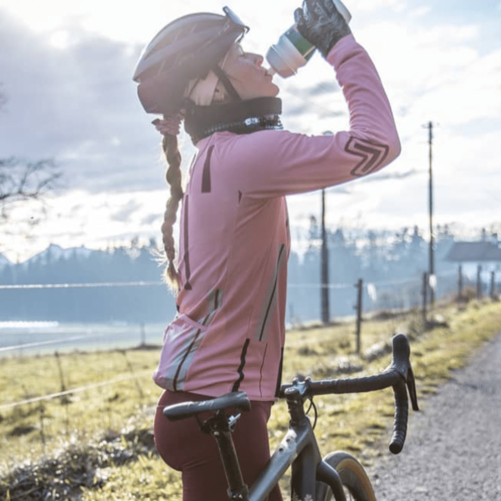 Radfahrerin in der Natur mit Trinkflasche in der Hand